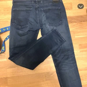 Replay Anbass jeans mörkblå, stl 32 - Säljer ett par snygga Replay Anbass jeans i mörkblå tvätt. Klassisk femficksmodell med raka ben och normal passform. Jeansen är tillverkade i mjukt denimtyg och har diskreta sömmar. Perfekta för dig som gillar stilrena och tidlösa jeans.