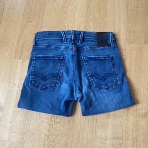Blå jeans från Replay Anbass - Snygga blå jeansshorts från Replay, modell Anbass. Klassisk femficksdesign med coola bakfickor och tydliga sömmar. Perfekta för sommaren och har en normal passform. Styla med en t-shirt eller hoodie för en chill look. 98cm längd.