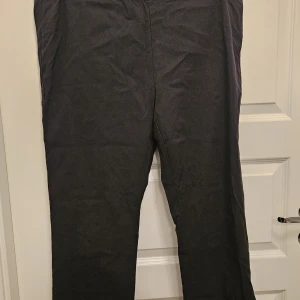 Stretchbyxa från Zhenzi storlek 50/52 - Svart stretchbyxa från Zhenzi med resår i midjan. Byxan har en rak passform. och är i gott använt skick.  Storlek 50/52 Längd 85 cm Midjebredd 100 cm