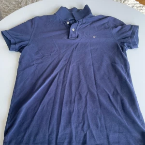 Blå pikétröja från Gant - Snygg ljusblå pike från Gant med klassisk krage och två knappar vid halsen. Strl S