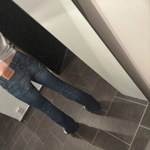 Levi's bootcut jeans blå - Säljer ett par klassiska Levi's jeans i blå tvätt med bootcut passform. Jeansen har normal midja, fem fickor och snygga slitningar framtill. Ikonisk läderpatch bak och orange sömmar. Perfekta för dig som gillar retrovibbar och tidlös denim. Skulle säga att dem motsvarar w24 l32 eller xxs 