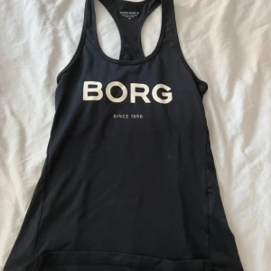 Svart träningstopp från Björn Borg  - Svart träningslinne från Björn Borg med stort vitt tryck på bröstet. Modellen har brottarrygg och är tillverkad i mjuk och stretchig polyester som sitter tight och följer kroppen snyggt. Är i helt nytt skick💗