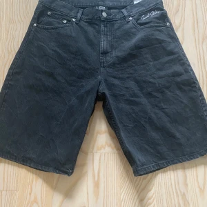 Svarta jeansshorts Sweet Skateboarding - Svarta jeansshorts från Sweet Skateboarding Company med broderad logga vid fickan och klassisk läderpatch bak. Modellen har fem fickor, bälteshällor och knappgylf. Materialet är slitstarkt denim och passformen är loose med midwaist. Jag hade inte sålt dem ifall de inte var för stora för mig.