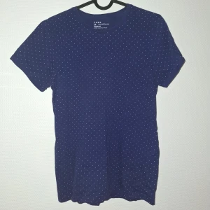 Mörkblå prickig t-shirt från FSBN - Snygg mörkblå t-shirt från FSBN i slim fit-modell. T-shirten har små vita prickar över hela tyget och är tillverkad i mjuk bomull. Perfekt för dig som gillar en enkel men ändå stilren look.