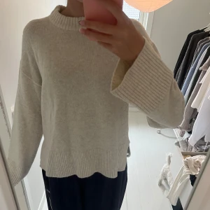 Beige stickad tröja - Mysig beige stickad tröja med vida armar. Tröjan har även en slits ner till. I storlek S och aldrig använd.