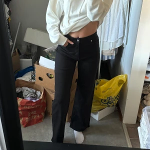 Svarta vida jeans med hög midja - Säljer ett par svarta jeans med hög midja och raka, vida ben. Snygg passform som sitter tajt över höften och släpper vid benen. Klassisk femficksmodell med knapp och dragkedja. Perfekta till sneakers eller boots. Aldrig använda.
