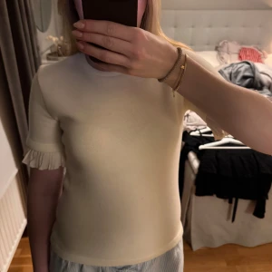 Vit topp med volang från Zara - En vit finstickad topp o stolek S från Zara. Den sitter figurnära och har tighta armar med volanger. En super fin topp men jag använder den inte eftersom jag inte trivs i den. Toppen är i fint skick. Hör gärna av dig vid frågor💗