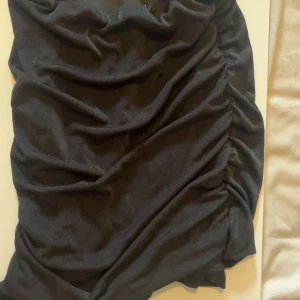 Svart kjol från SHEIN XS - Säljer en svart kjol från SHEIN i storlek XS. Kjolen har snygga rynkade detaljer längs sidorna som ger en cool och trendig look. Materialet är mjukt och stretchigt, perfekt för dig som gillar slim passform och vill ha en kjol som sitter snyggt.