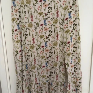 Blommig långkjol från objekt - Superfin långkjol med blommigt mönster i pastelliga färger från objekt. Kjolen har volang nertill och resår i midjan för en bekväm passform. Perfekt för vår och sommar när du vill ha en luftig och söt look.