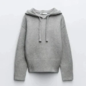 Grå stickad tröja Zara  - Mysig grå stickad hoodie med huva och snörning. Tröjan har långa ärmar och bred ribbad mudd vid ärmslut och nederkant. Perfekt för lager-på-lager och chill dagar.
