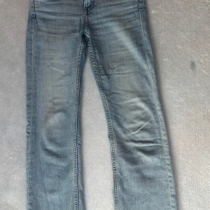 Blå jeans från Kappahl, stl 140 - Snygga ljusblå jeans från Kappahl i klassisk rak modell. Jeansen har slitningar och snygg tvätt, samt bakfickor med knappdetalj. Perfekta för en avslappnad och cool stil.