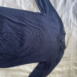 Mörkblå långärmad tröja från H&M - En basic mörkblå långärmad tröja från H&M i storlek M. Tröjan har rund halsringning och är tillverkad i ett mjukt material som passar perfekt till lager-på-lager. Enkel och stilren design utan mönster eller detaljer.