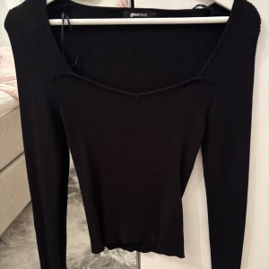  ribbad topp Gina Tricot - Snygg svart ribbad tröja från Gina Tricot med lång ärm och v-ringad hals. Modellen är slim och har en cool detalj med söm framtill som ger en unik look. Perfekt att styla med jeans eller kjol för en trendig vibe. Perfekt för alla tillfällen. Endast använd en gång och tvättad inför försäljning.
