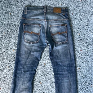 Nudie Jeans Lean Dean W30 L32 - Snygga blå jeans från Nudie. Modellen är Lean Dean och har storleken W30 L32. De är allmänt i bra skick, dock har de blivit lagade an Nudie tidigare (se sista bilden). De har en sliten look vilket är väldigt snyggt och efterfrågat. Skriv vid minsta fundering om mått eller liknande!