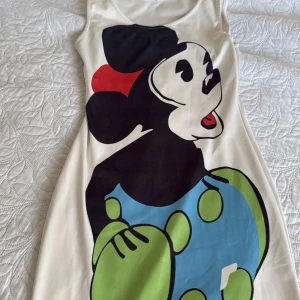 Vit klänning med Minnie Mouse - Säljer en vit klänning med stort tryck av Minnie Mouse. Materialet känns mjukt och lätt, perfekt för dig som gillar färgglada och lekfulla prints. Den kan användas hemma men även ute. Kan användas som olika storlekar passar alla dvs xs, s, m och l