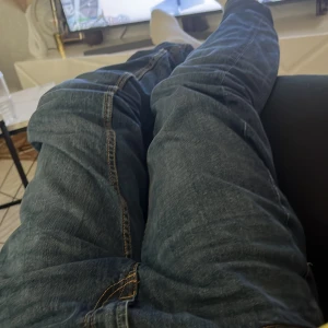 Blå jeans med rak passform - Säljer ett par klassiska blå jeans med rak passform och snygga kontrastsömmar. Jeansen har normal midja och är tillverkade i slitstarkt denimtyg. Perfekta för dig som gillar en enkel och tidlös stil.