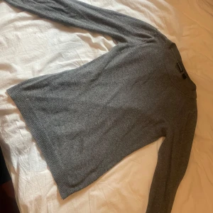 Grå stickad tröja från Selected Femme - Mjuk och enkel grå stickad tröja från Selected Femme. Tröjan har rund halsringning, långa ärmar och ribbade muddar vid ärmslut och nederkant. Perfekt för lager-på-lager och passar till allt.