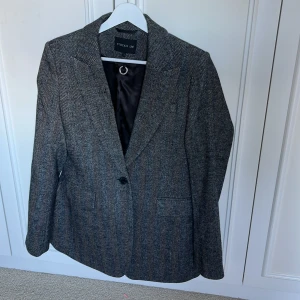 Grå kavaj i ullmix - Superfin knappt använd kavaj i ullmix från STOCKH LM (MQ), fiskbensmönster i grått och svart (ser grått ut). Slits baktill!