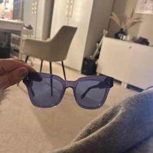 CHIMI glasögon - Snygga lila solglasögon från ACAI med transparent plastbåge och rektangulär form. Glasen är mörka och ger en cool vibe, perfekt för dig som vill sticka ut med färg. Bågarna har diskreta silverdetaljer vid gångjärnen och är lätta att bära.