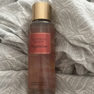 Victoria's Secret Temptation mist - Fräsch och fruktig body mist från Victoria's Secret i doften Temptation. Flaskan är genomskinlig med rosa etikett och guldig kork. Doften har inslag av saftig äpple och blommor. Den är ej använd då jag använder andra perfymer som ja har. 