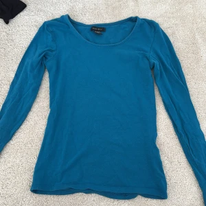 Blå långärmad tröja från Amisu XS - Enkel och stilren blå långärmad tröja från Amisu i storlek XS. Tröjan har rund halsringning och är gjord i mjuk bomull, perfekt för lager-på-lager eller som den är. Snygg passform som sitter nära kroppen.