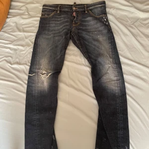 Mörkblå Dsquared2 jeans - Snygga mörkblå jeans från Dsquared2 med slitningar och distressed detaljer. Jeansen har skinny passform, klassiska fem fickor och kontrastsömmar. Perfekta för dig som gillar en edgy streetstil. Materialet är jeans med stretch för extra komfort.