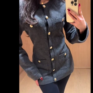 Cardigan med guldfärgade knappar - Snygg mörkgrå kofta med guldfärgade knappar från H&M. Tygbom har används på öppningen vid knapparna så man kan inte ha den öppet. Annars är den i jätte fin skick. 🫰🏼