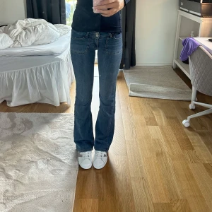 Blå low waist bootcut jeans från Nelly - Snygga blå jeans från Nelly som inte säljs på hemsidan längre med bootcut passform och låg midja. Jeansen har framfickor, bakfickor med lock. Köpta för 699 kr. Storlek 34 och stretchigt material. De har inga slitningar eller andra tecken på andvändning. Innerbenslängd 82 cm. Skriv om intresserad eller andra frågor 🩷