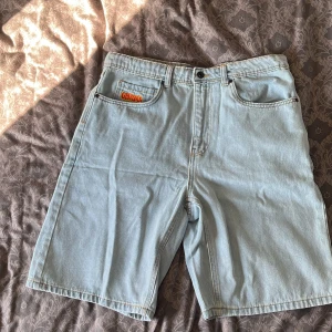Empyre jeansshorts - Empyre Relax Loose Fit jeansshorts i ljusblå denim med klassisk femficksdesign och coola grafiska detaljer på bakfickan. Shortsens loose fit ger en avslappnad vibe och de har midwaist passform. Perfekt för dig som gillar streetstyle och vill ha bekväma shorts. Köpt av en polare och har sedan dess inte använt de, då jag tycker de är lite för baggy. Helt nya aldrig använt. Skriv om frågor! Stl 32