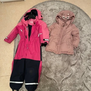 Brun pufferjacka med huva och öron - Säljer en brun pufferjacka med söt huva som har broderade ögon och små öron. Jackan är vadderad och har långa ärmar, perfekt för kalla dagar. Stängs med dragkedja och har fickor  framtill. Mysig och trendig för vintern! Passar barn mellan 8-9 år 