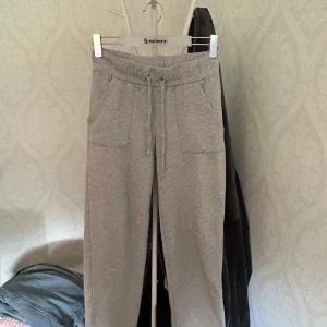 Grå mjukisbyxor med snörning - Grå mjukisbyxor med dragsko i midjan och två stora fickor framtill. Byxorna har en avslappnad passform och är perfekta för chill dagar. Liten fläck på byxbenet.