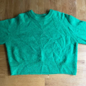 Grön stickad tröja från C.W. - Snygg grön stickad tröja från C.W. i storlek XXS. Jag har dock använt denna och har storlek S/M. Tröjan har rund halsringning, ribbade muddar och är långärmad - den är även cropped i modellen. Perfekt för dig som gillar färg!