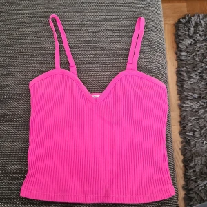 Ribbad rosa linnetopp från Zara - Säljer en ribbad rosa linnetopp från Zara med smala justerbara axelband och snygg v-ringning. Toppen är croppad och har en figurnära passform, perfekt för att lyfta vilken outfit som helst. Tillverkad i mjuk bomullsmix som känns skön mot huden.