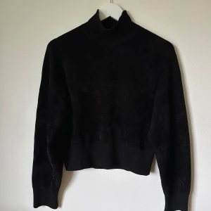 Svart polotröja från & Other Stories - Svart polotröja från & Other Stories med hög krage och långärmad design. Tröjan har en clean och stilren look, är lite loose i passformen och är tillverkad i en mjuk blandning av viskos, polyamid, polyester och elastan. Perfekt för dig som gillar minimalistisk stil. 1F10