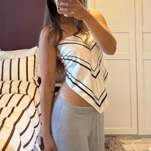 Vit bandeau tubtopp med svarta ränder - Säljer en vit bandeau tubtopp som även kan användas som scarf. . Materialet är glansigt och känns som satin.