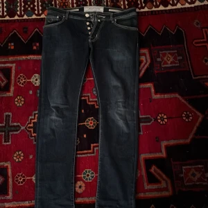 Mörkblå jeans från Jacob Cohën Style 622 - Snygga mörkblå jeans från Jacob Cohën med kontrastsömmar och klassisk femficksdesign. Jeansen har knäppning med flera silverfärgade knappar och detaljerad brodyr på bakfickorna. Perfekta för dig som gillar stilrena och tidlösa jeans. Skriv om ni har frågor👍
