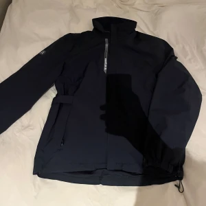 Mörkblå vindjacka från Abacus - Säljer en svart vindjacka från Abacus i storlek 160 cm. Den passar ca 150-164 cm. Säljer eftersom den är för liten. Den har ej några defekter. Hör av er om minsta fundering💫