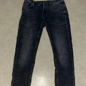 Svarta jeans från SMOG, storlek 31W/32L - Säljer ett par svarta jeans från SMOG i storlek 31/32. Jeansen har en klassisk design och en stilren look
