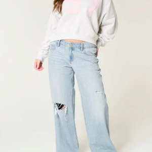 Ljusblå Low waist jeans med slitningar - Säljer ett par ljusblå jeans med breda ben och snygga slitningar på låret dom är Low waist