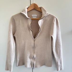 Beige kofta från Tiger of Sweden - Beige kofta från These glory days som har tre hål(ett lagat) som man kan se på bilden den skulle passa dig som är mellan 150-160 koftan är i materialet merino ull. Hör av er vid minsta fundering