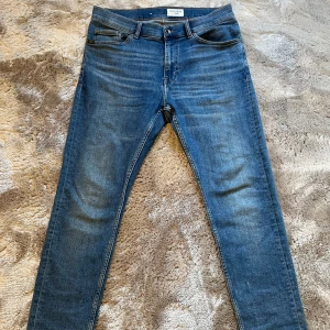 Blå jeans från Tiger of Sweden - Snygga blå jeans från Tiger of Sweden i väldigt bra skick och med en normal passform och är tillverkade i slitstarkt denim. Alltså lite ”stretch” men sjukt sköna. Storleken syns på bilden och är 33/32 men skulle säga att dom passar till en större midja ändå då dom är lite ”stretch”. Hör av dig om du har någon fråga!