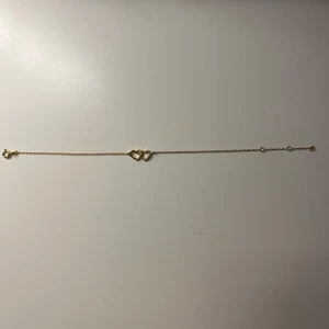 Guldarmband med hjärtan - Elegant guldarmband med två sammanlänkade hjärtan. Perfekt som en subtil och stilren accessoar för alla tillfällen. Inga defekter.