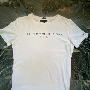 Vit t-shirt från Tommy Hilfiger - Säljer en stilren vit t-shirt från Tommy Hilfiger, storlek är 164 men har krympt i tvätten, skriv om ni har några frågor 