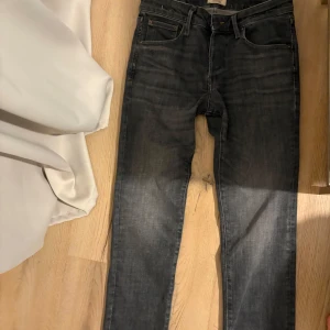 Svarta slim straight jeansbyxor - Snygga svarta jeansbyxor med en klassisk femficksdesign. De har en knappgylf och är i storlek W30. Perfekta för en stilren look. Byxorna är endast använda 2 gånger och passformen är L30 W30. Nypris är ca 950 kr. Vid bättre bild på insidan av jeansen hör av dig!