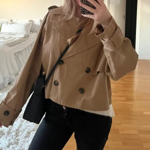 Beige croppad trenchcoat  - Superfin beige trendig trenchcoat från Gina Tricot med dubbelknäppning, en kortare modell (croppad) 🌸 slutsåld på hemsidan. Endast använd några få gånger, då den tyvärr är för stor för mig.