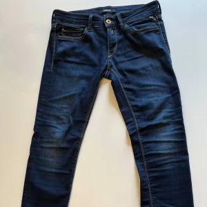 Replay Jeans mörkblå - Snygga mörkblå jeans från Replay med klassisk femficksdesign och guldfärgade sömmar. Jeansen har en normal passform och är perfekta för en stilren look. Märkesdetaljer syns på fickan och bakfickan har en diskret broderad logga. Har en liten slitning på lappen på insidan (se på bild nr 5) annars är jeansen i toppskick, och som nya✨Nypris ligger på runt 1000-1299 kr💸 mitt pris 599kr. Priset är inte hugget i sten 🪨, Hör av er vid minsta lilla fråga❓eller fundering 🤔Mvh Sigge🤙🥂
