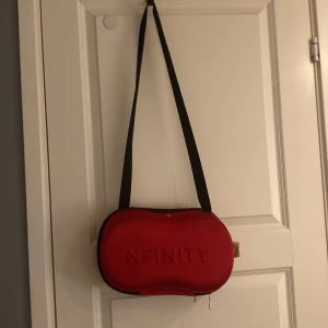 Röd/rosa axelväska från Nfinity , cheerleading skor från nfinity strl 42 - Säljer en röd axelväska från Nfinity med svart axelrem. Väskan har en dragkedja och är perfekt för att förvara skor eller andra småsaker. Den är kompakt och lätt att bära med sig. På väskan finns en liten fläck som tyvärr inte går bort! Men väskan är super fin ändå!!