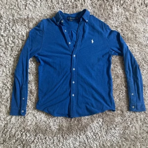 Blå långärmad skjorta från Ralph Lauren - Tjena! En asfet blå långärmad skjorta från Ralph Lauren med klassisk krage och knappar framtill. Skick 10/10, pris kan diskuteras!