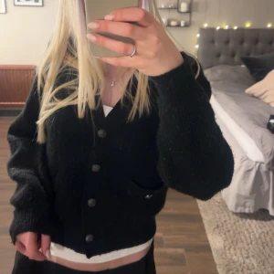 Svart kofta med knappar - Säljer en mysig svart kofta med knappar framtill. Koftan har långa ärmar och en klassisk design.