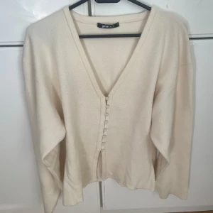 Vit kofta från Gina Tricot - Säljer en stilren vit kofta från Gina Tricot med v-ringning och knappar framtill. Perfekt för lager-på-lager under kyligare dagar. Är i storlek S☀️